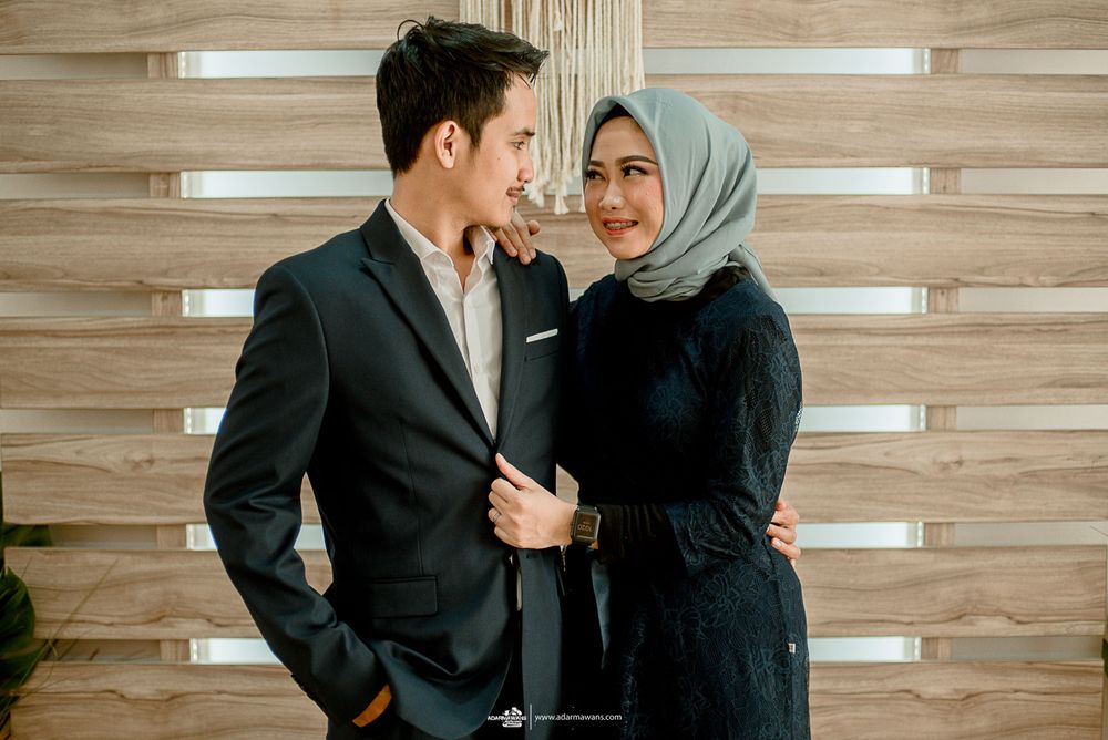 Stylish couple shares an intimate moment against wooden panel wall background.