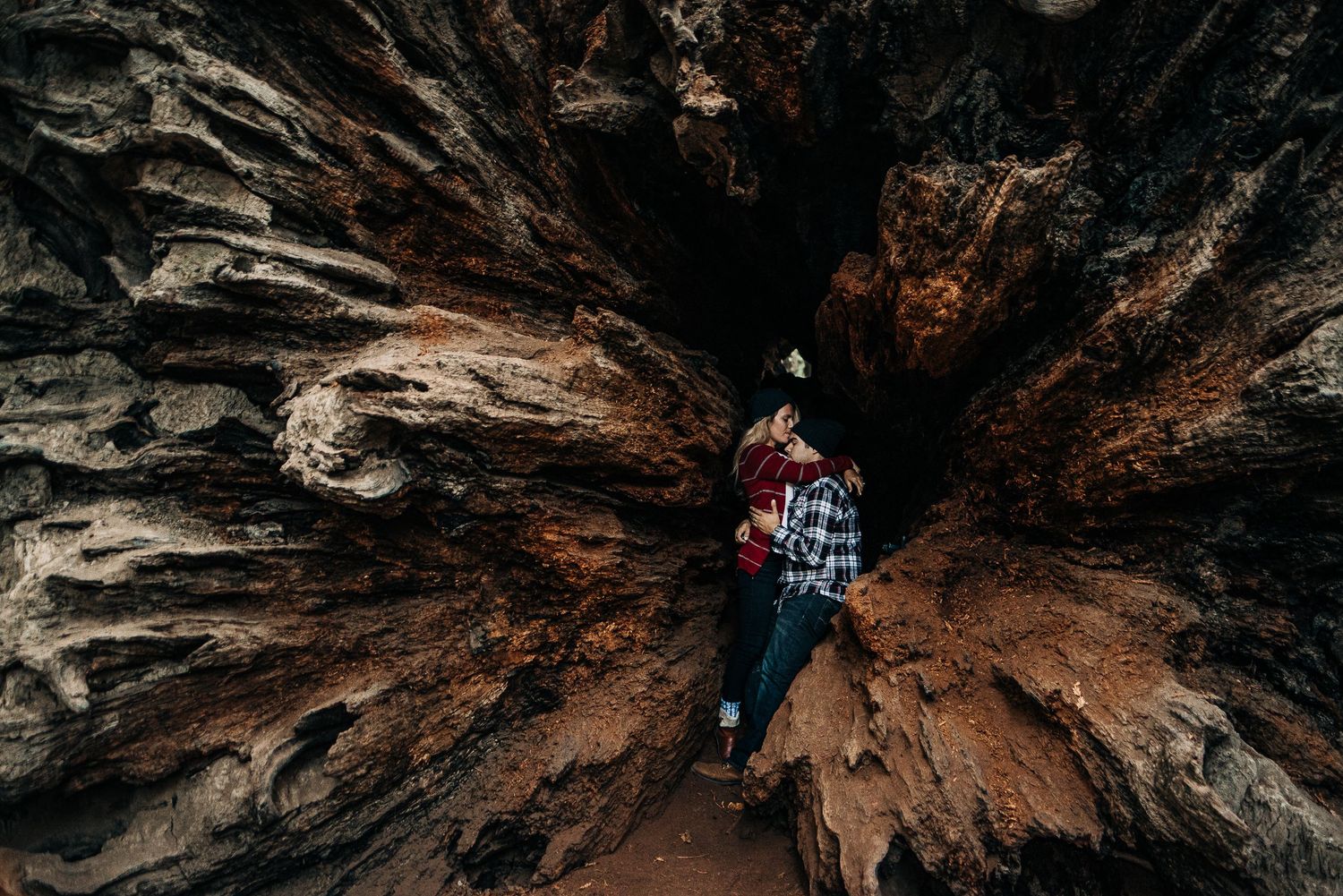 An adventurous explorer examines rock formations inside a dramatic cave structure.