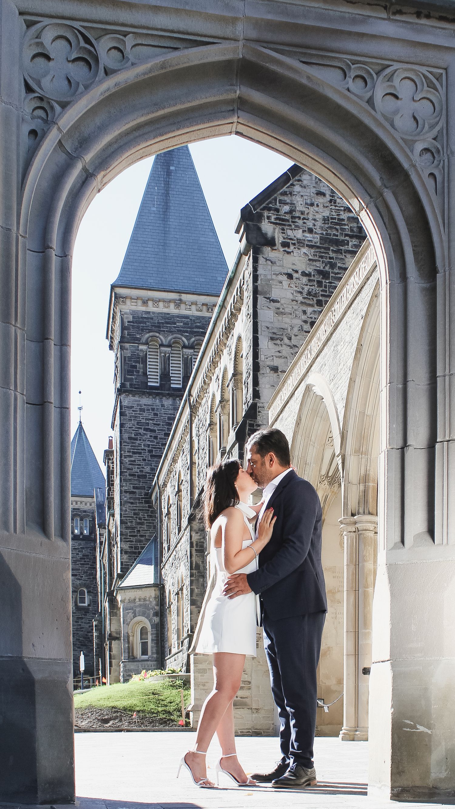 Couple sharing an intimate moment under a Gothic stone archway with church architecture in the background.