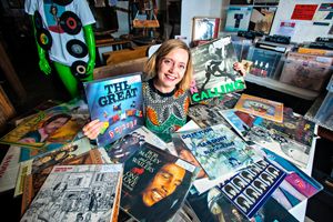 Creative professional surrounded by graphic novels and artwork in studio setting.