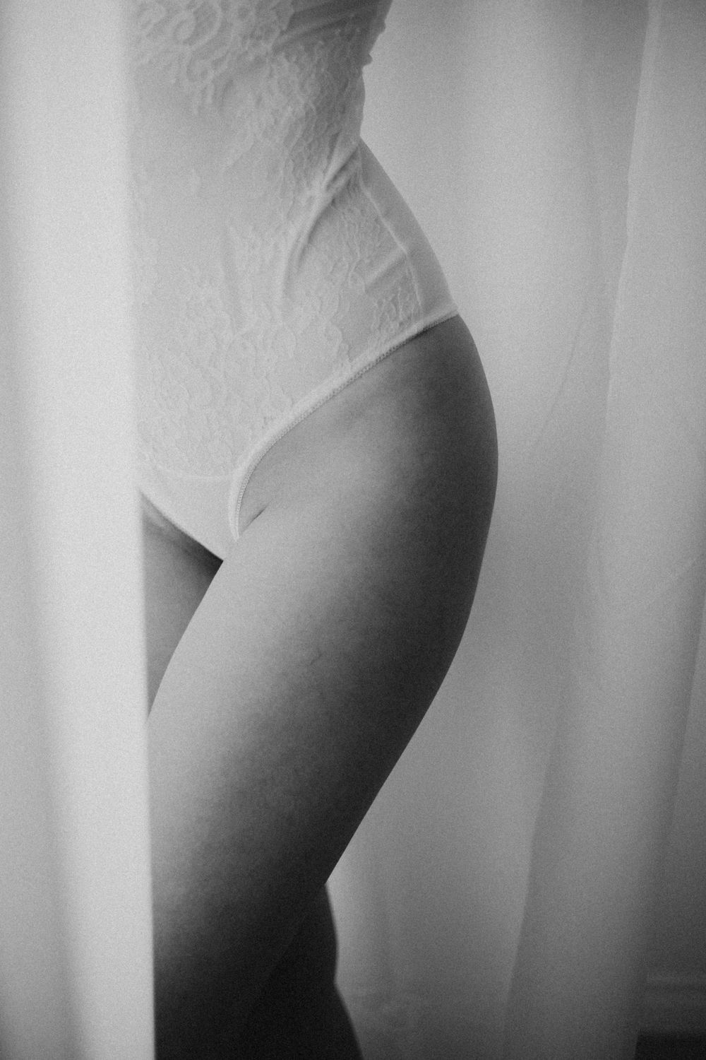 Sensuelli boudoir-kuvaus Helsingissä, nainen valkoisissa alusvaatteissa ikkunavalossa