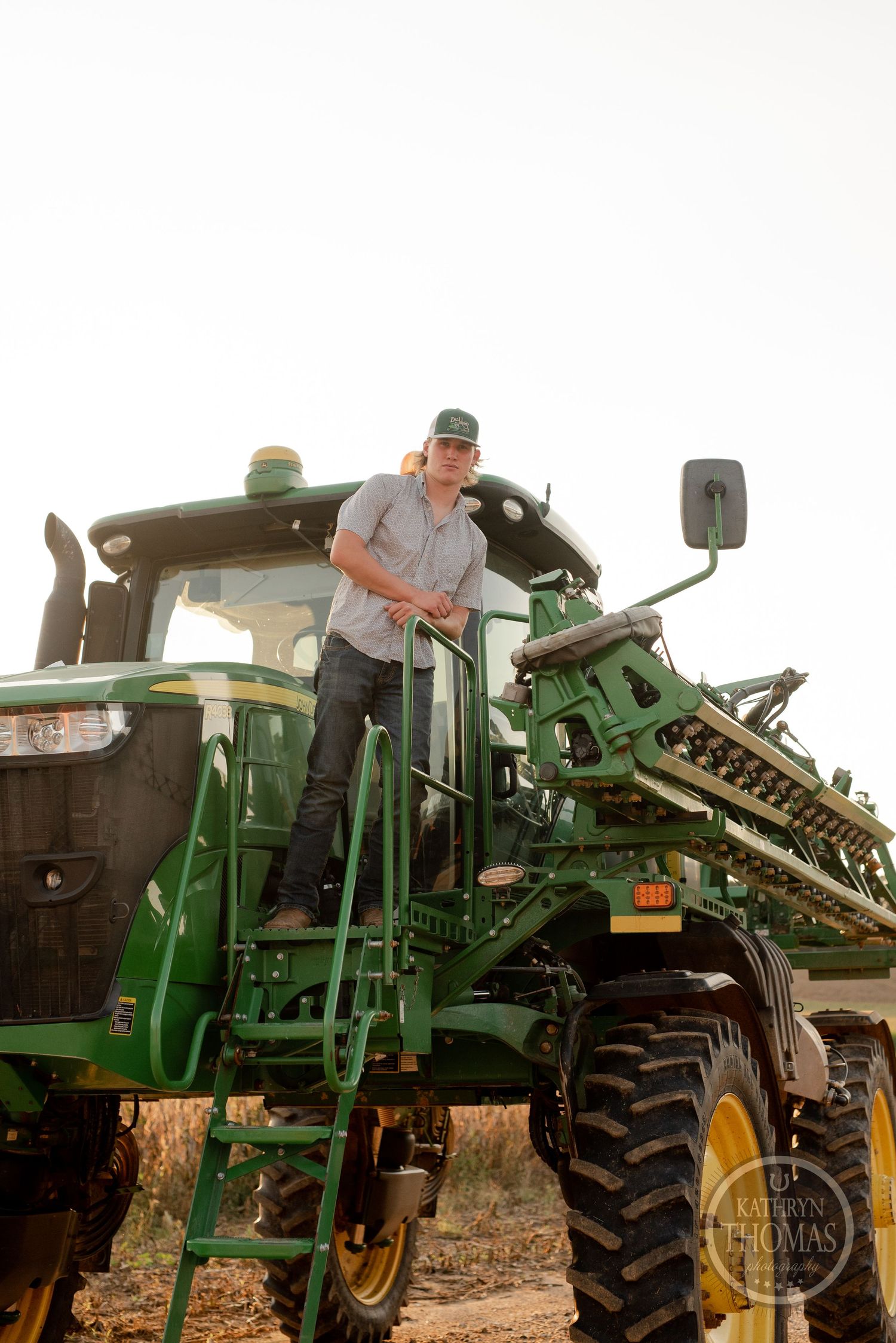 Low angle view of a farmer on the platform of a modern John Deere agricultural sprayer.