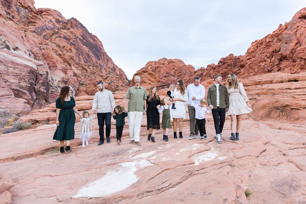 Group photo of wedding party on red rock formations in desert landscape.