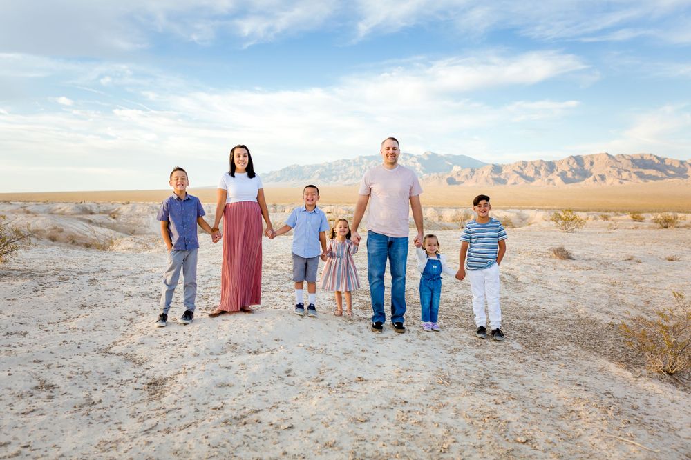 Family walking together in desert landscape with mountains and blue sky.