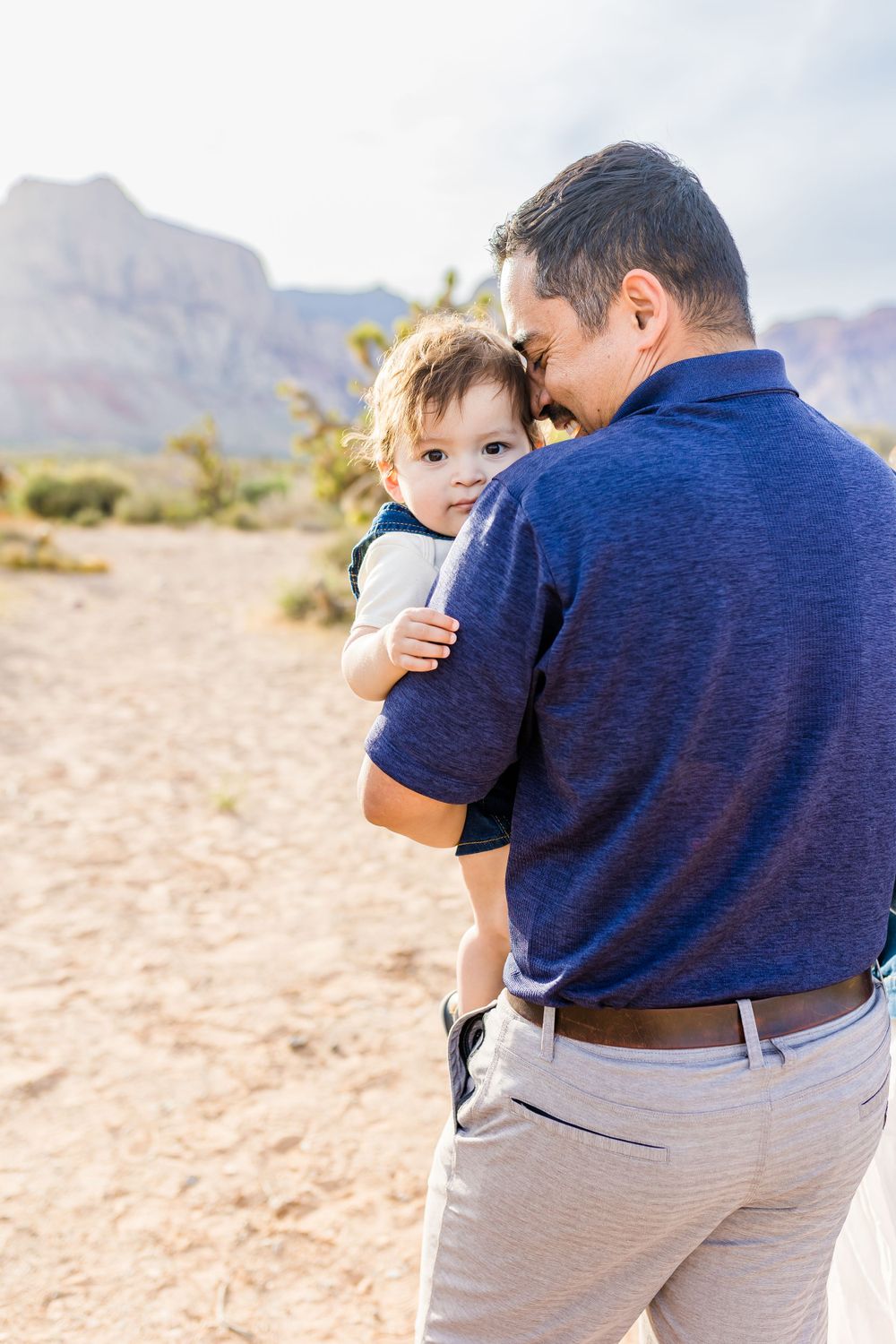 Parent and child sharing tender moment against desert mountain backdrop.