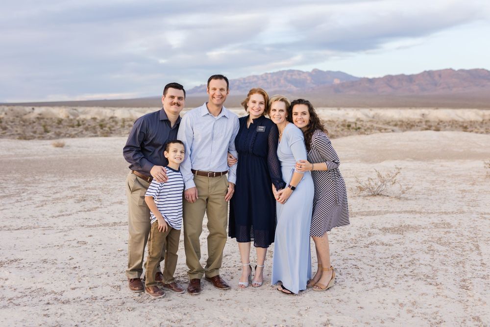 Group portrait in desert landscape with mountains in background.