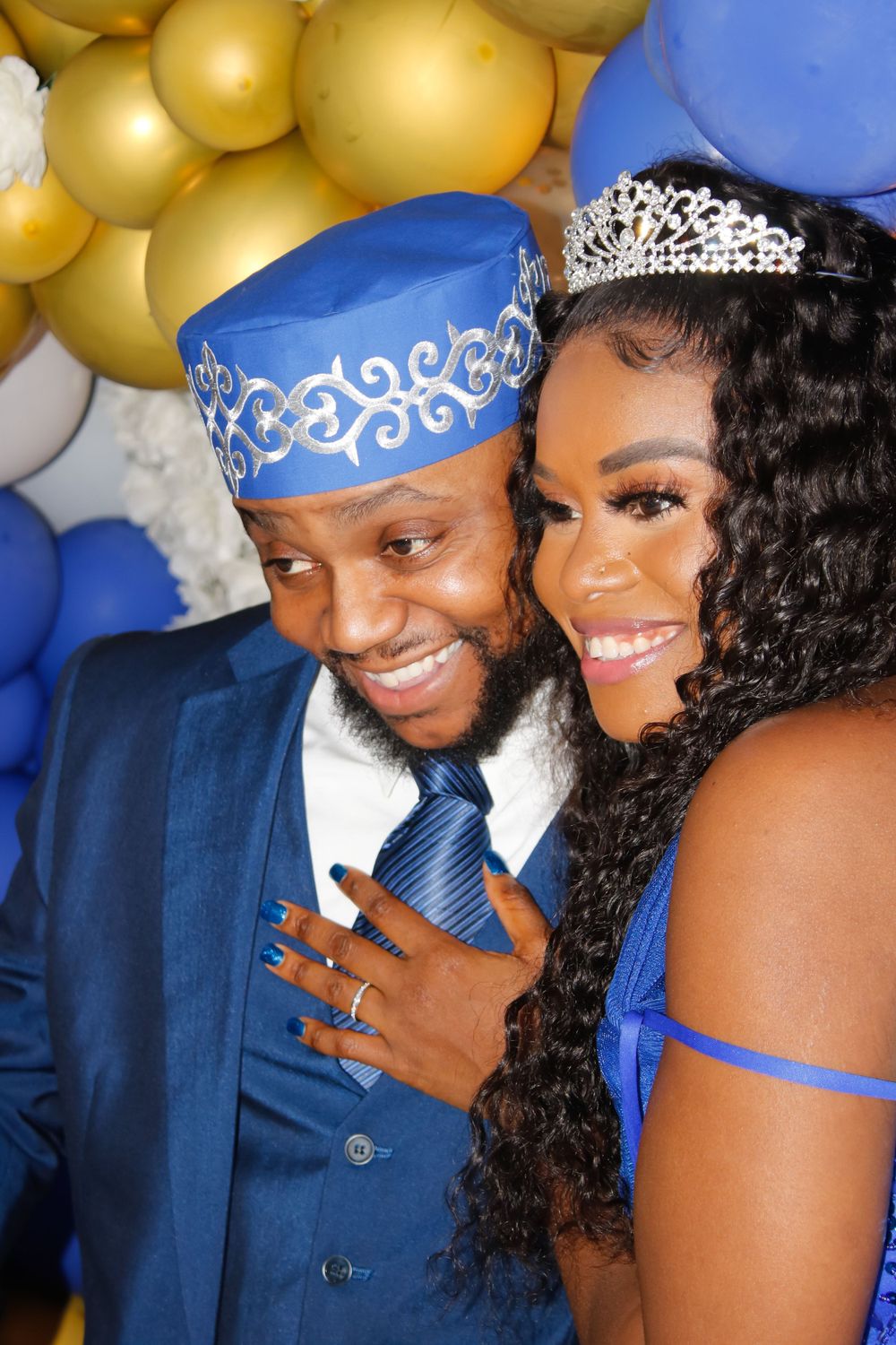 Formal couple photo with blue and gold balloon backdrop and matching accessories.