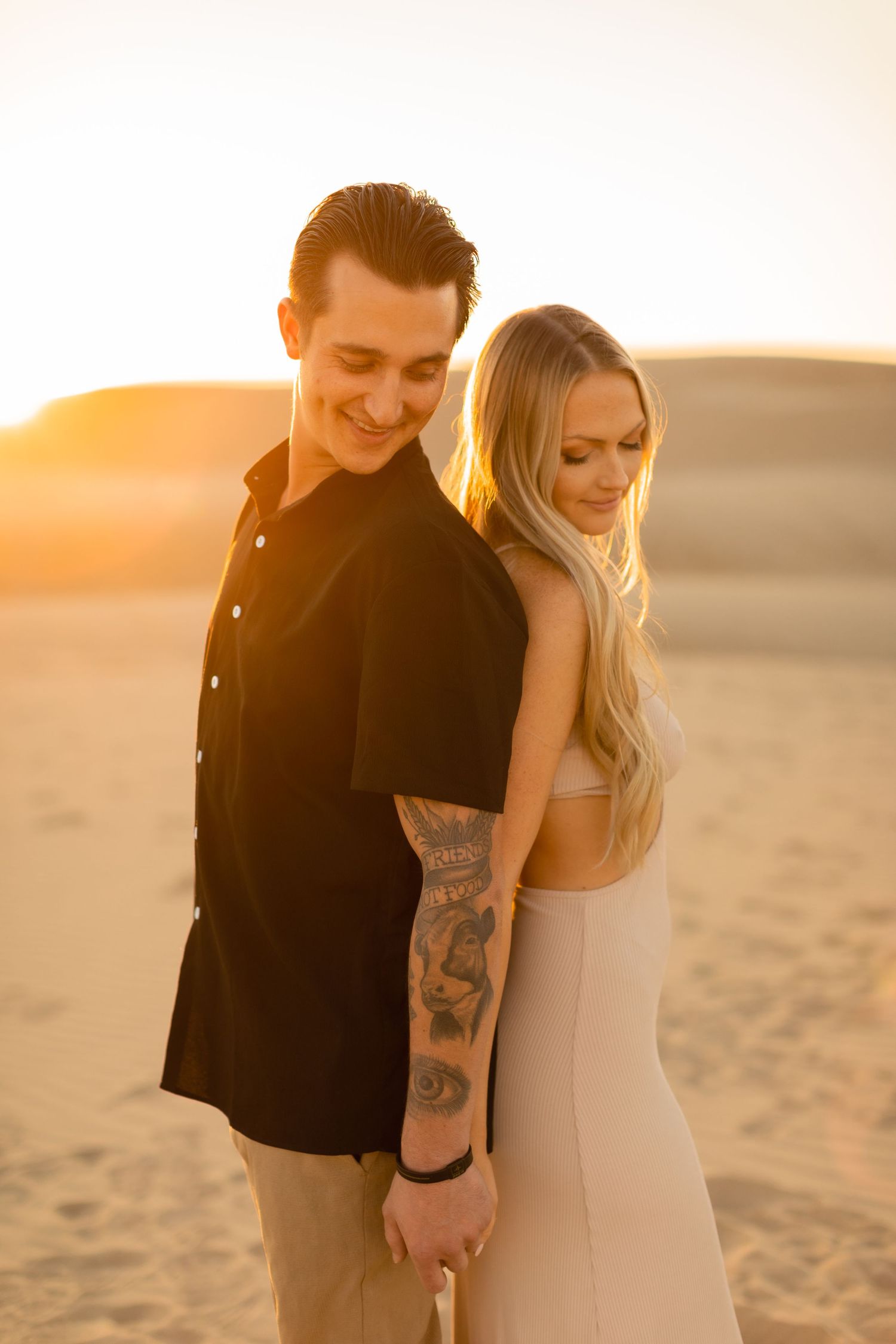 Couple sharing intimate moment on desert dunes during golden hour.