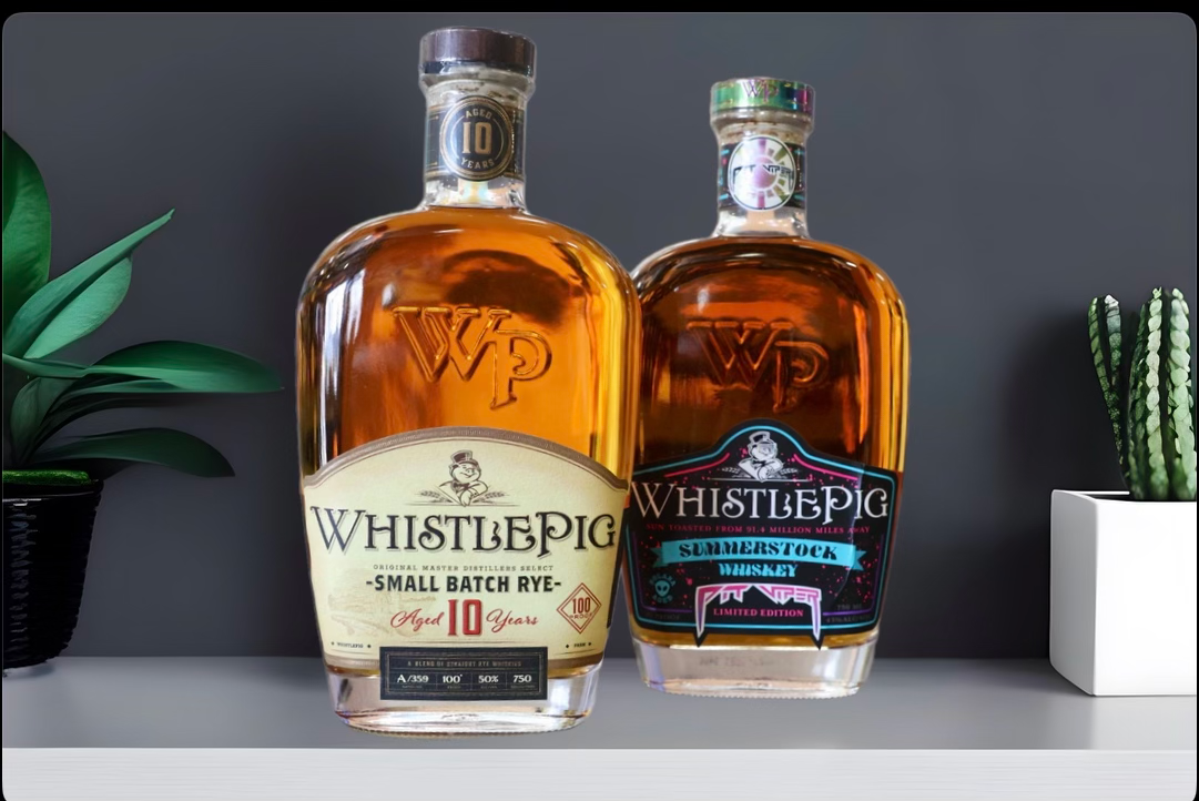 Two bottles of WhistlePig whiskey displayed on a shelf with decorative plants in the background.