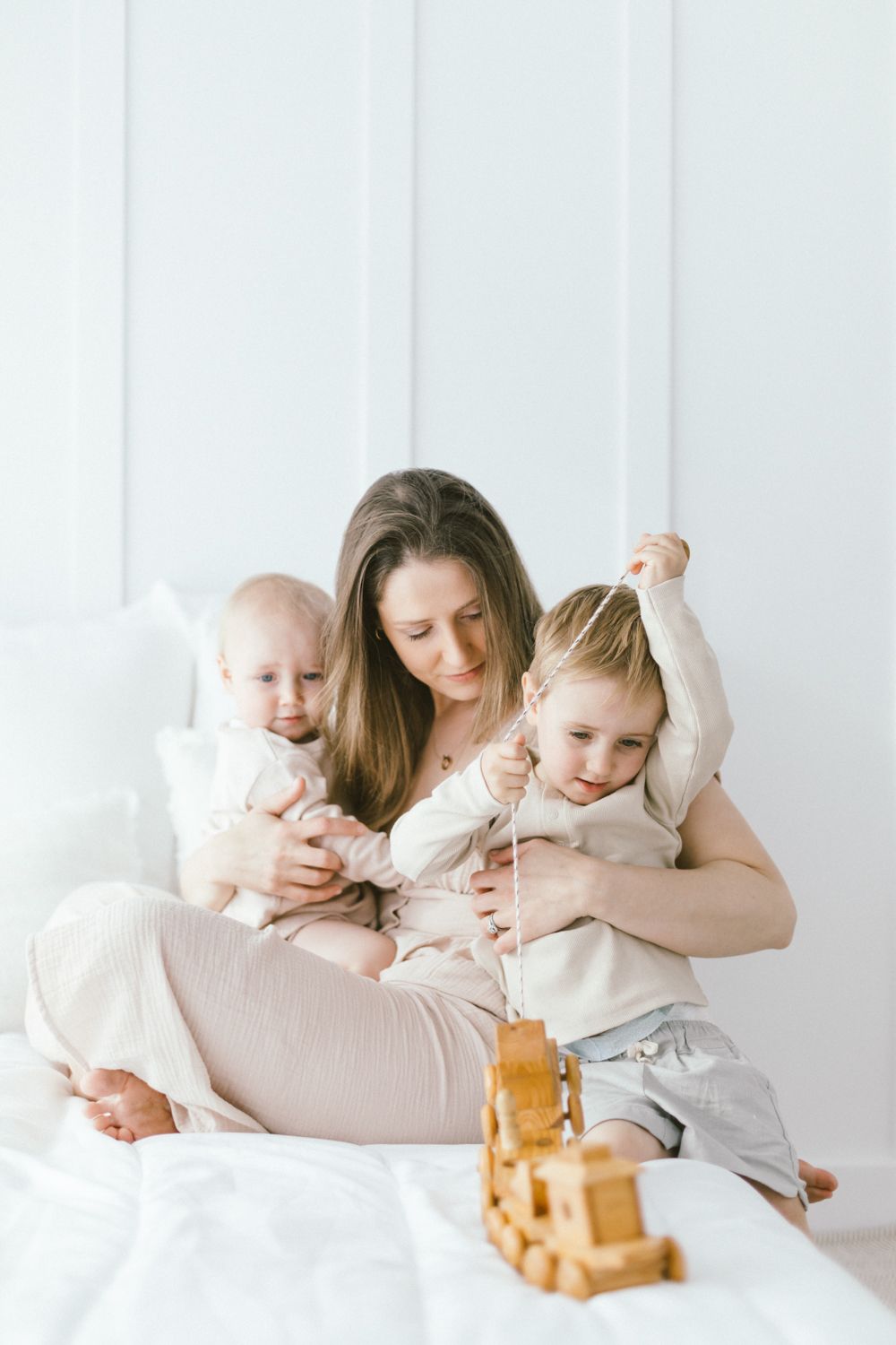 Playful family scene with wooden toys in soft neutral colors.