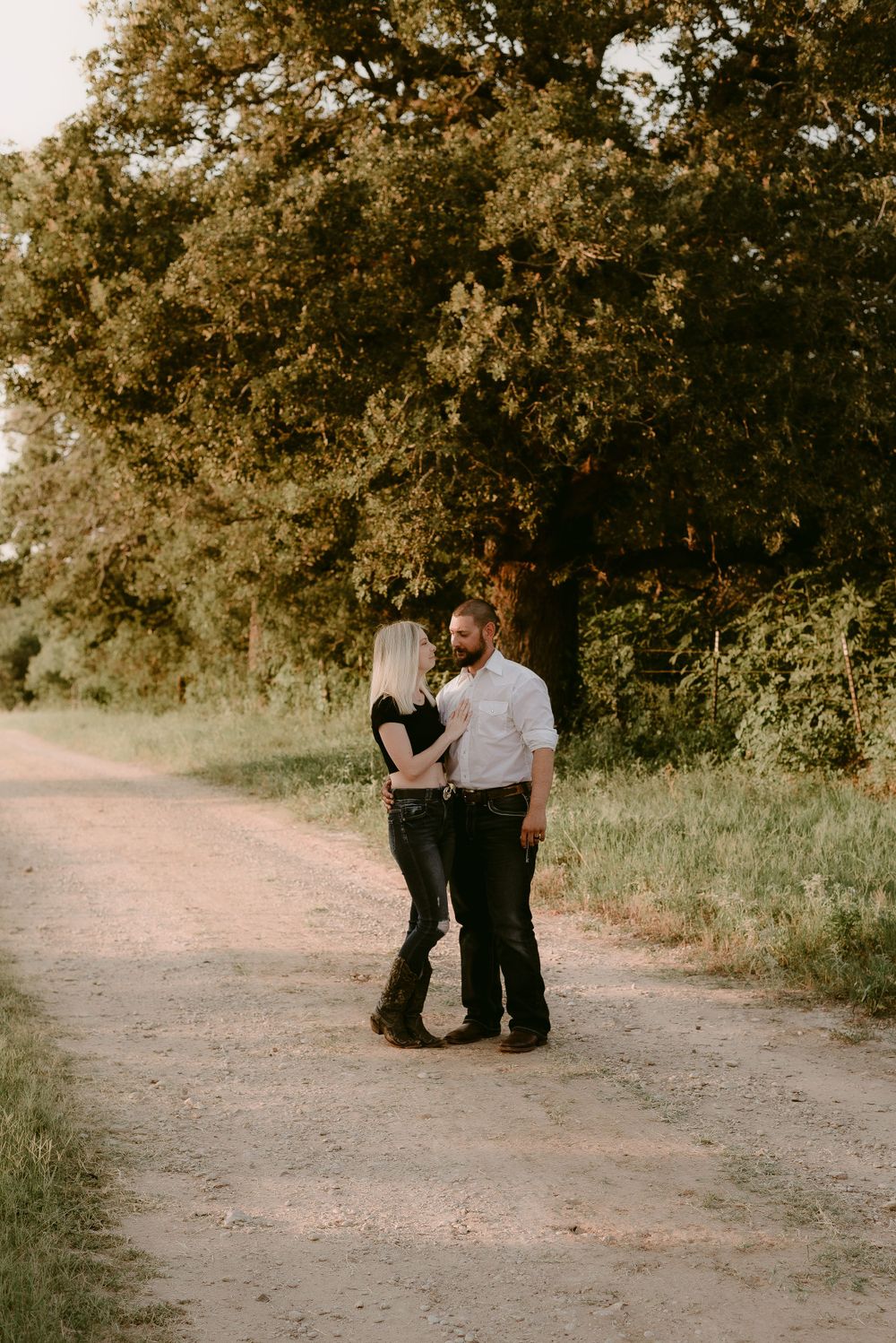 Intimate couple portrait on a dirt path surrounded by trees.