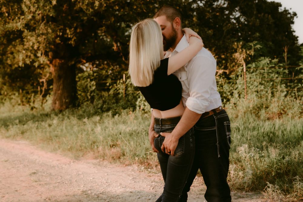 An intimate embrace between a couple on a rustic path with warm sunset lighting.