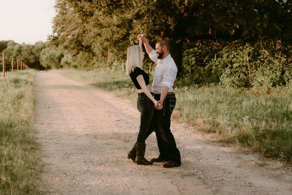 A couple dances together on a rustic dirt path during golden hour.