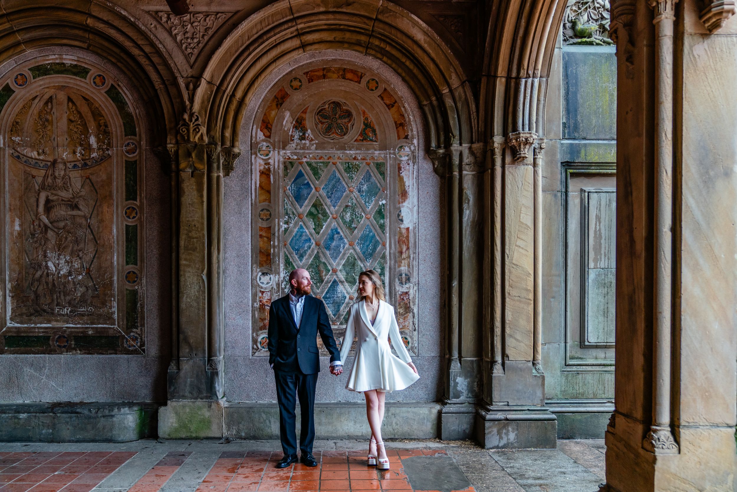 A couple stands in a romantic archway at Bethesda Terrace in Central Park, New York City.