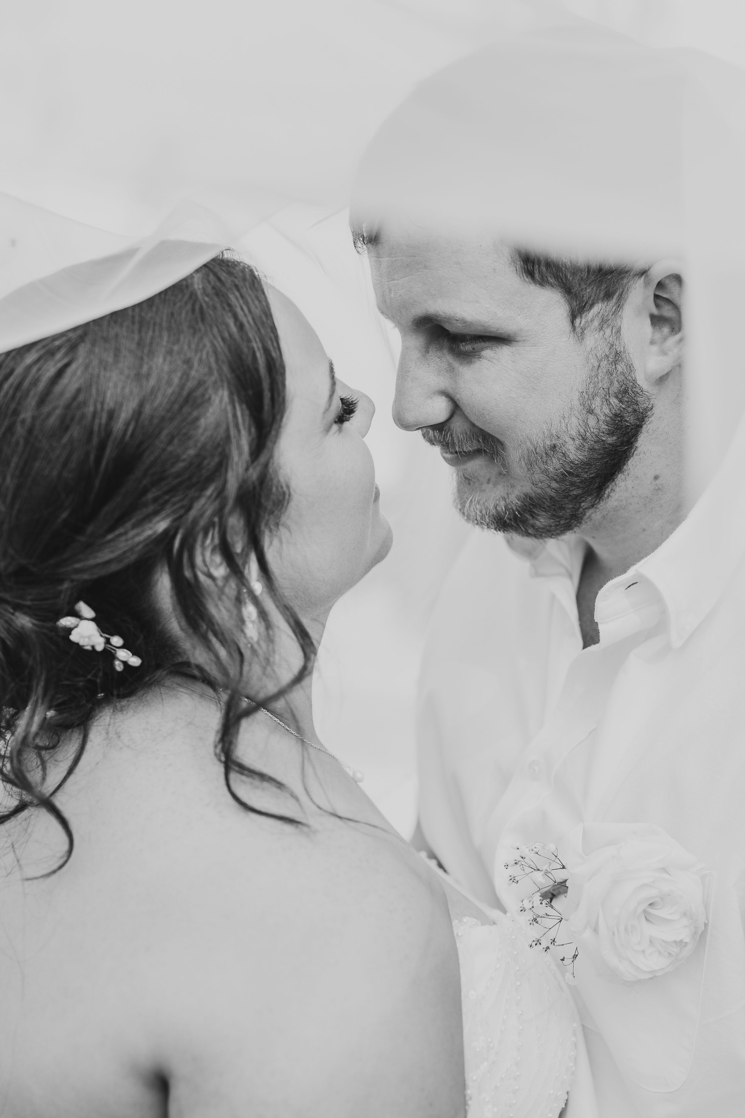 An intimate black and white portrait of a bride and groom gazing at each other in a romantic moment.