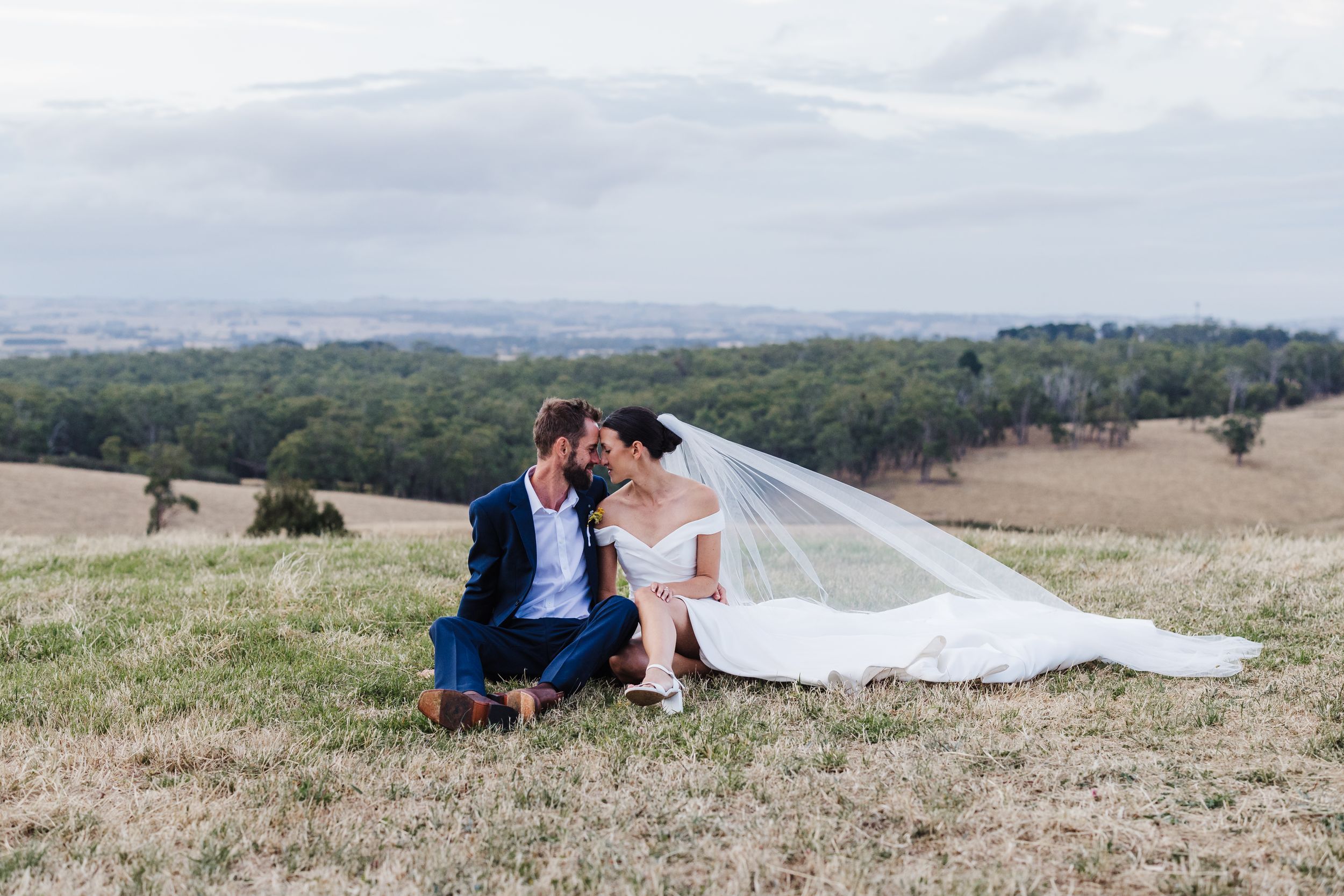 Intimate wedding moment captured on grassy hillside with mountain views. Koonwarra.