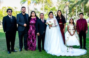 Wedding party group photo outdoors with palm trees in the background.