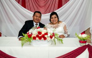 Wedding couple seated at reception table with red and white decor.