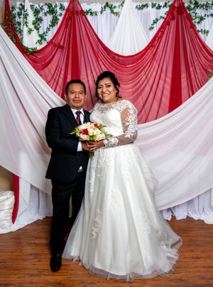 Wedding ceremony setup with red and white draped backdrop and floral garland decorations.