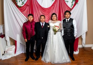 Wedding party formal photo against red and white draped backdrop.