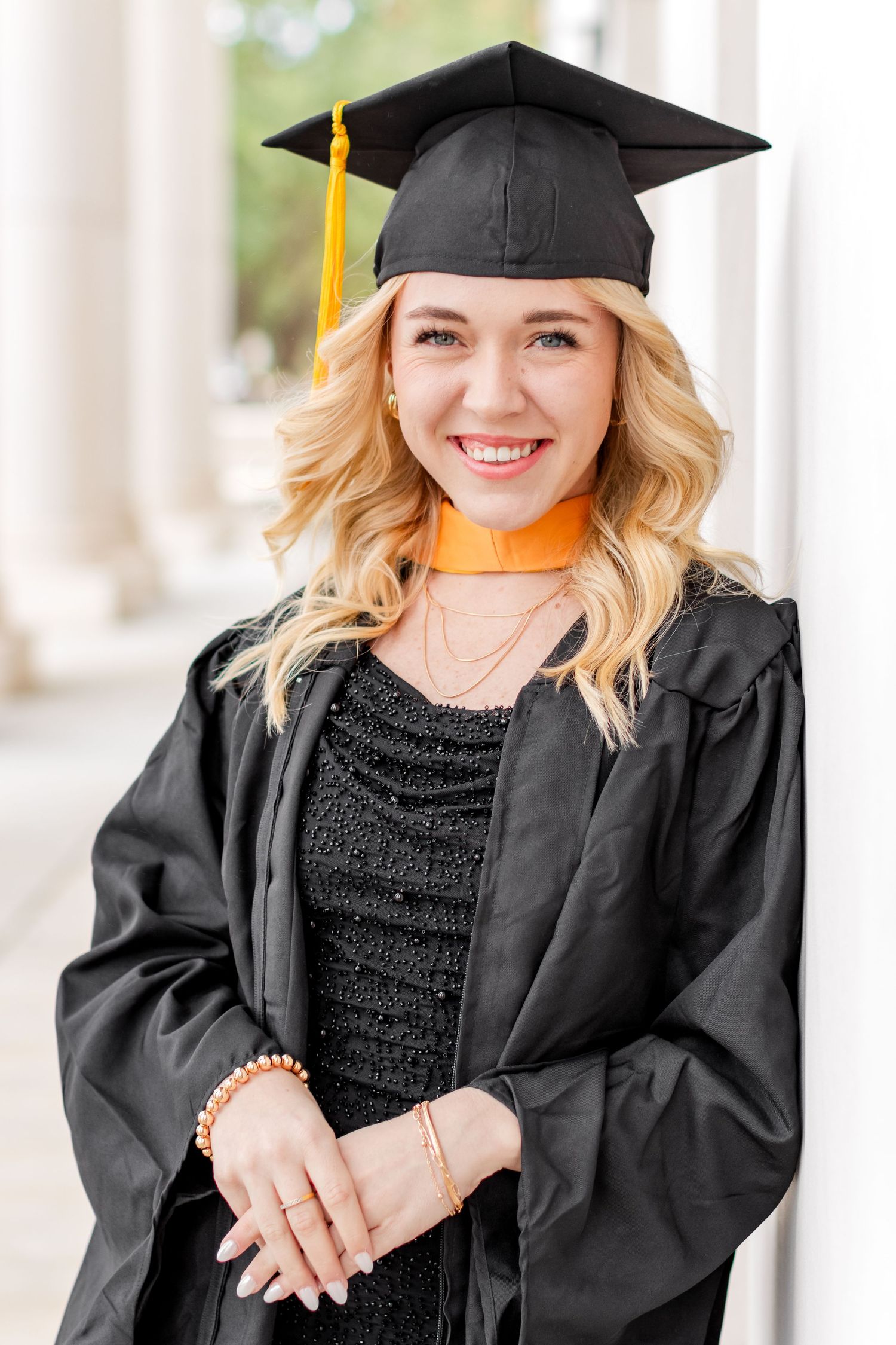 Graduate with cap and gown smiling in the hallway of her university on Mississippi