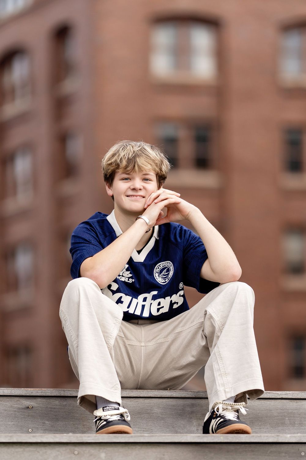 Senior photo of a boy sitting at the top of a stairway and looking down taken by Milwaukee senior photographer Rachel Dickman.