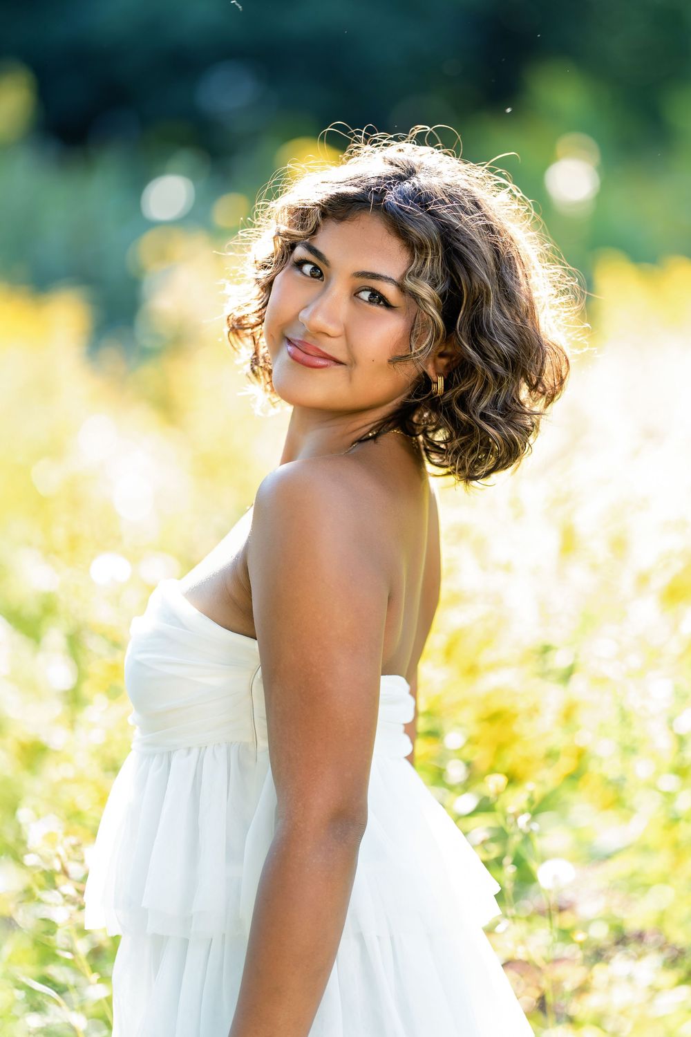 Senior photo of a girl backlit in a field looking over her shoulder taken by Milwaukee senior photographer Rachel Dickman.