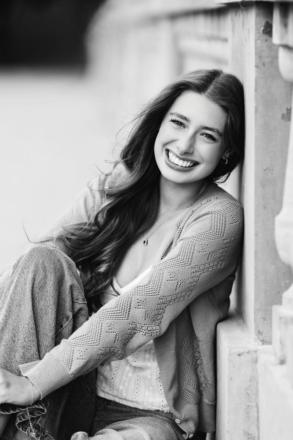 Black and white senior photo of a girl sitting and  leaning on a fence taken by Milwaukee senior photographer Rachel Dickman.