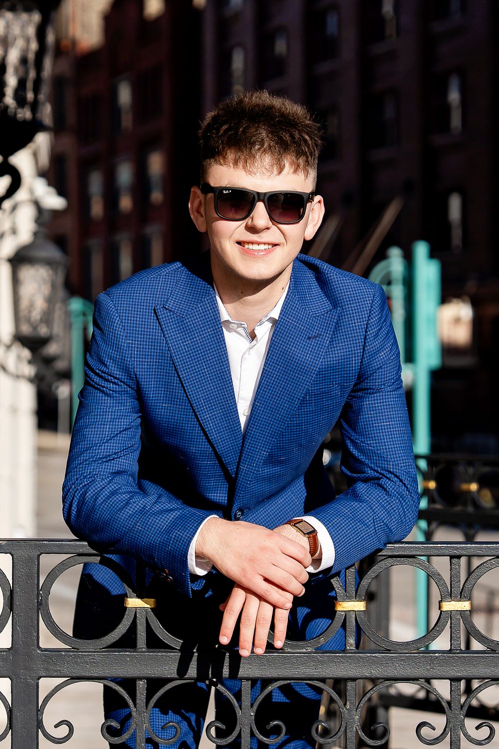 Senior photo of a boy leaning on a fence wearing his sunglasses taken by Milwaukee senior photographer Rachel Dickman.