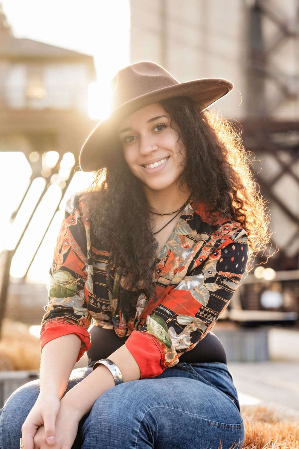 Senior portrait of girl smiling in fedora with sunset backdrop - shot by Milwaukee senior photographer Rachel Dickman.
