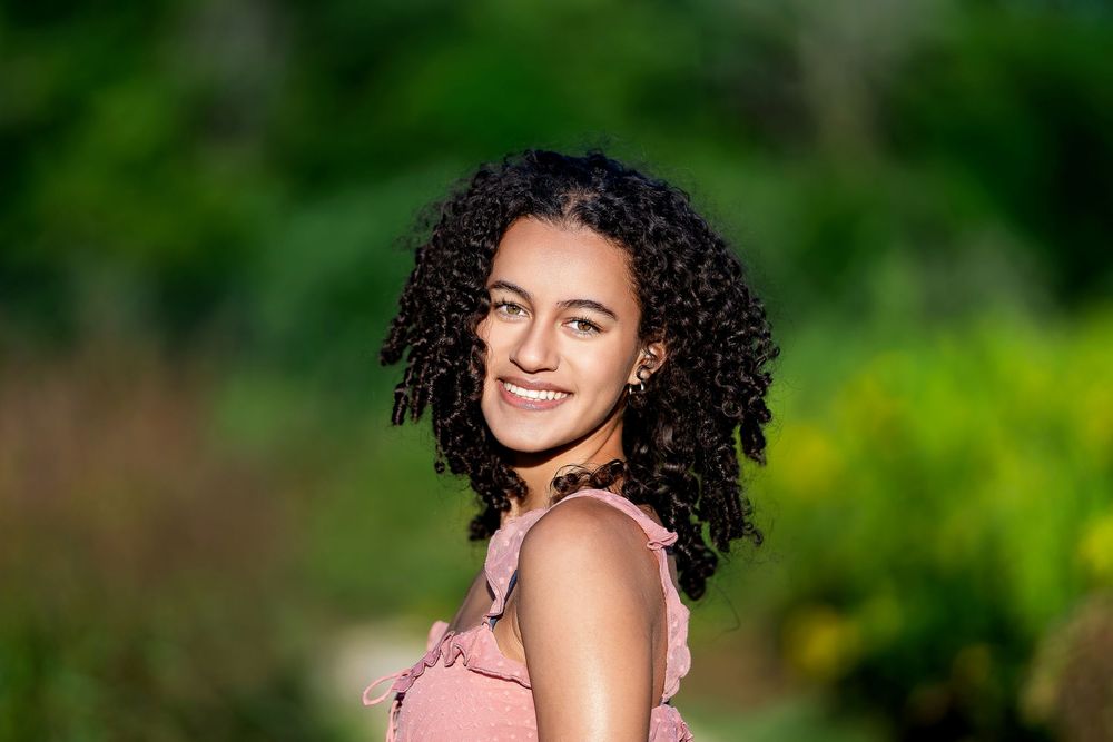 Senior photo of a girl looking over her shoulder and smiling in a natural setting taken by Milwaukee senior photographer Rachel Dickman.