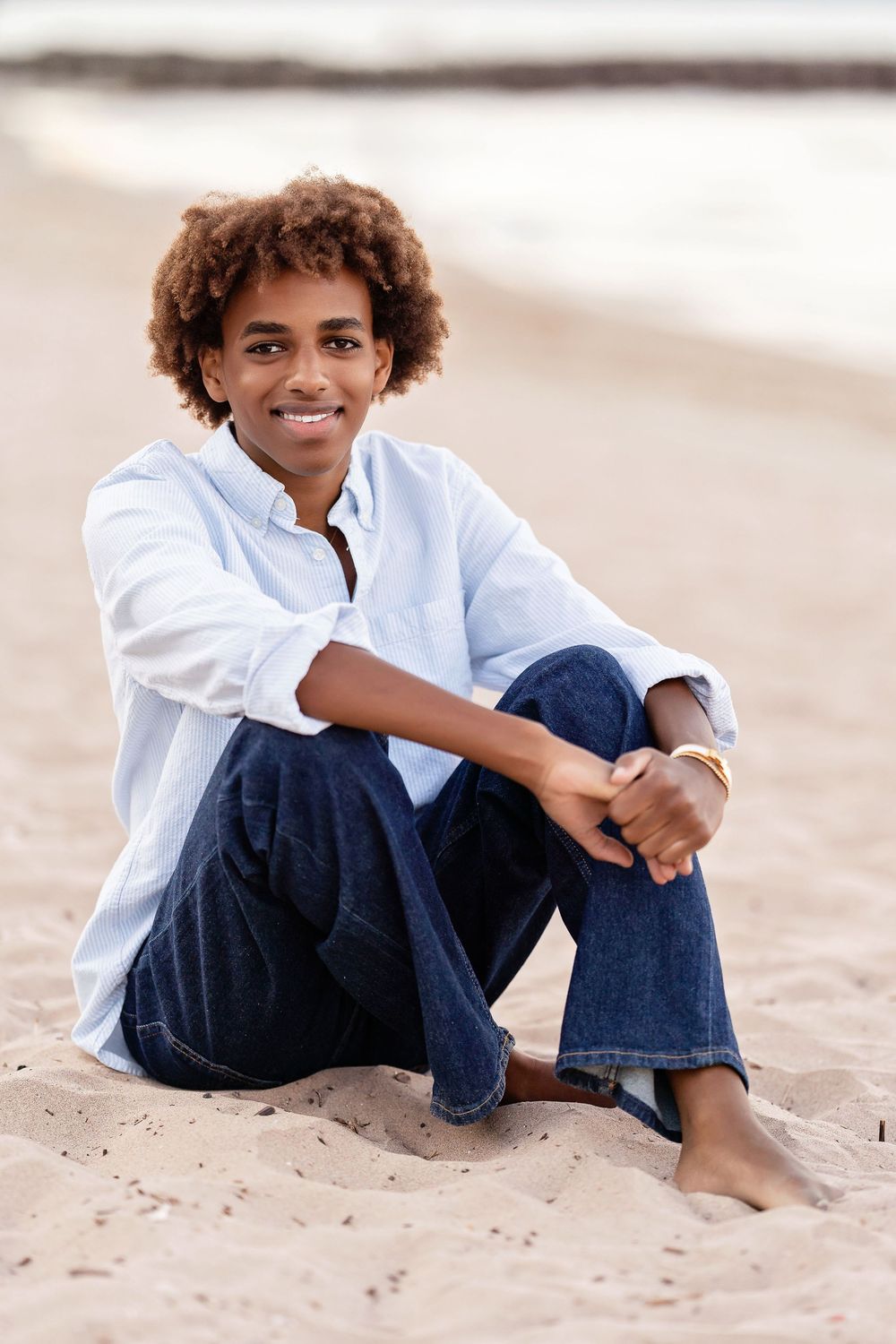 Senior photo of a boy sitting with his arms on his knees on the beach at sunset taken by Milwaukee senior photographer Rachel Dickman.
