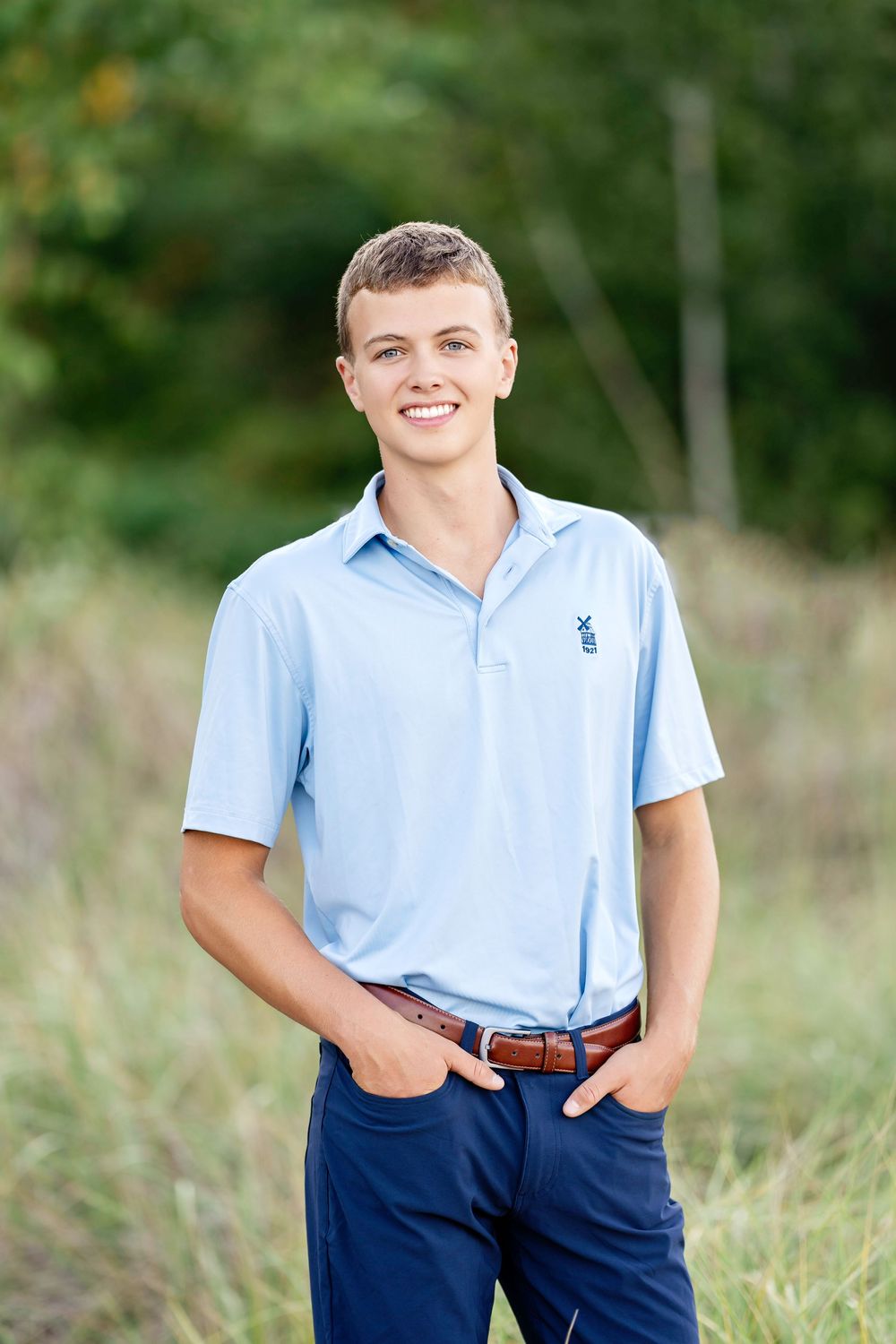Senior photo of a boy standing with his hands in his pockets and smiling taken by Milwaukee senior photographer Rachel Dickman.