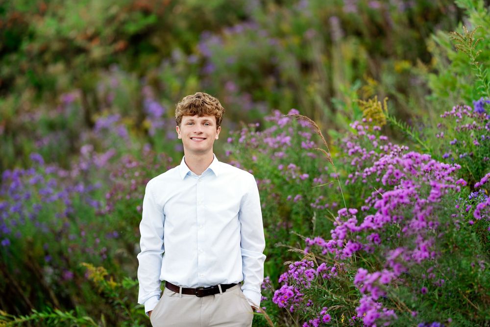 Senior photo of a boy standing in a field of purple flowers with hands in pockets taken by Milwaukee senior photographer Rachel Dickman.