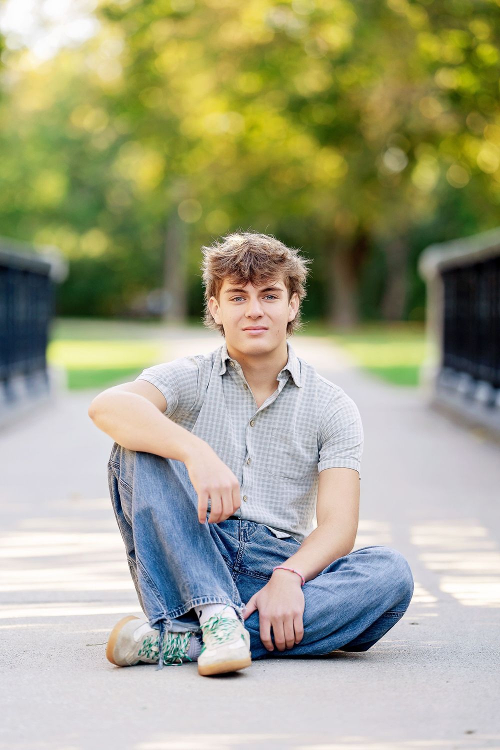 Senior photo of a boy sitting on a bridge taken by Milwaukee senior photographer Rachel Dickman.