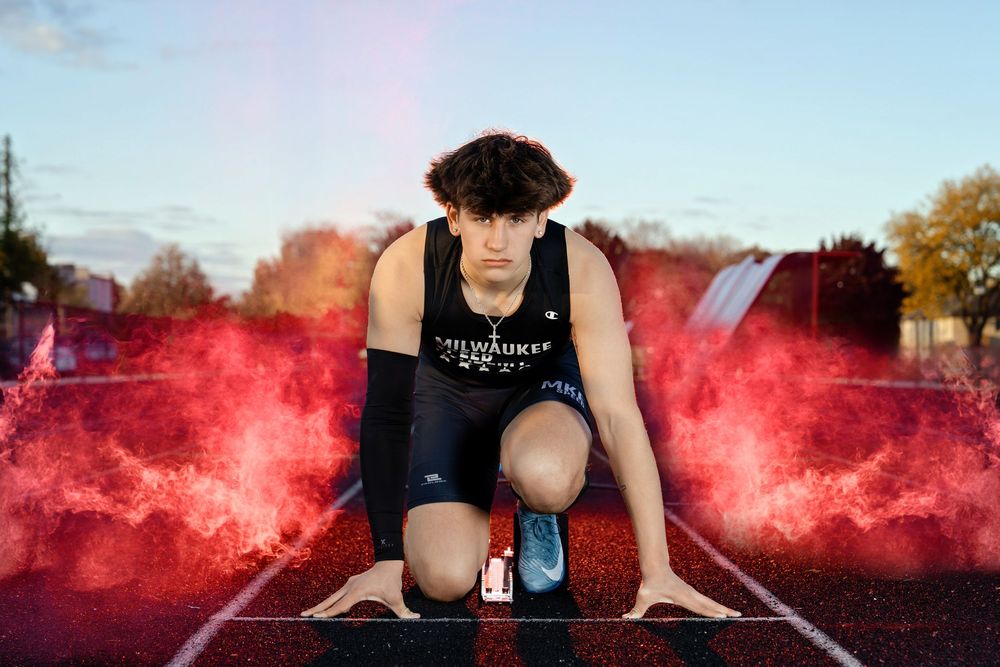 Senior photo of a boy in starting blocks on a track with smoke and lights behind him taken by Milwaukee senior photographer Rachel Dickman.
