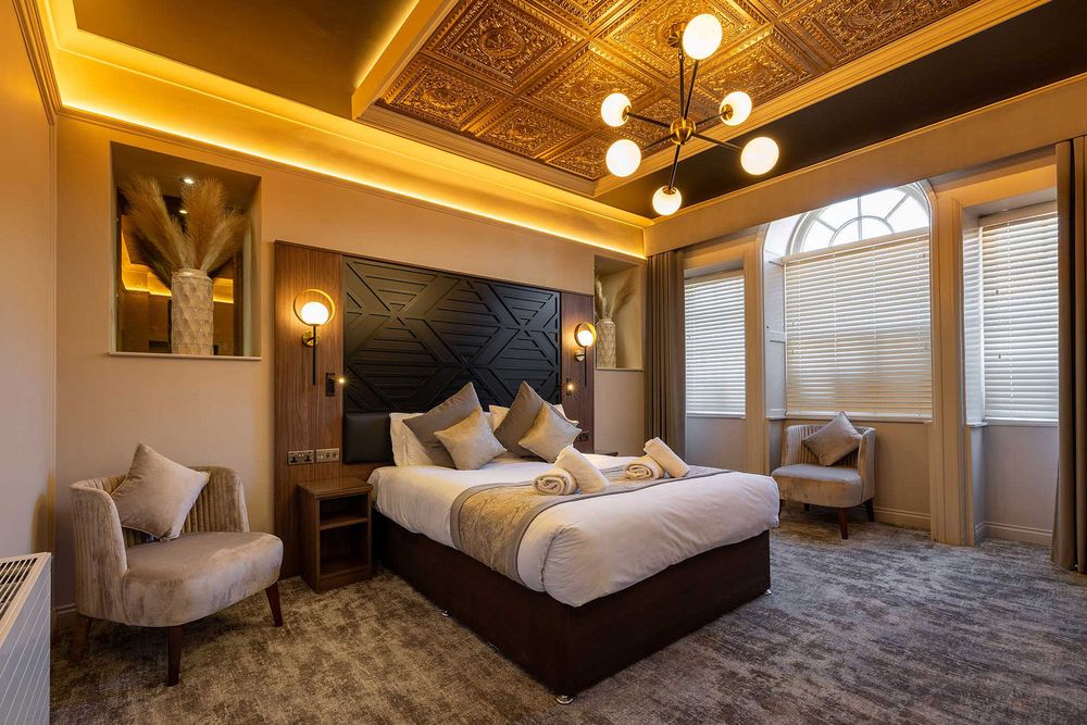 Luxury hotel bedroom with elegant lighting, ornate ceiling details and contemporary furnishings in a stylish boutique interior.