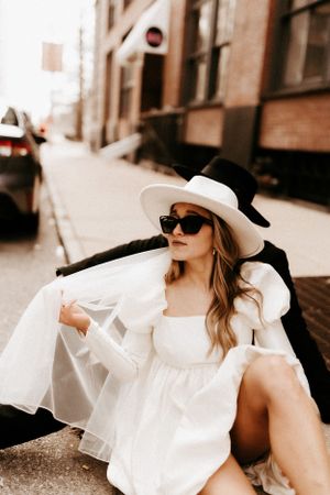 Stylish street fashion photograph featuring a flowing white dress and wide-brimmed hat.