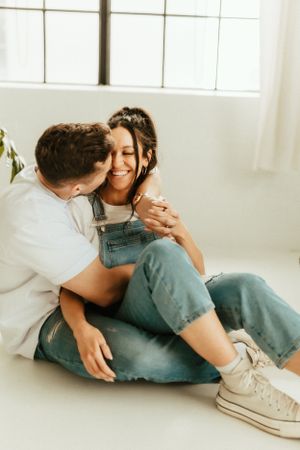 Intimate lifestyle portrait in casual denim against a bright white studio setting.