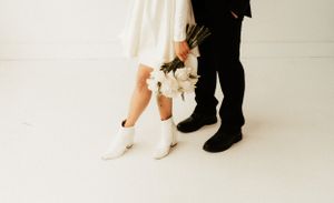 Close-up of formal footwear showing white boots and black dress shoes on white floor.