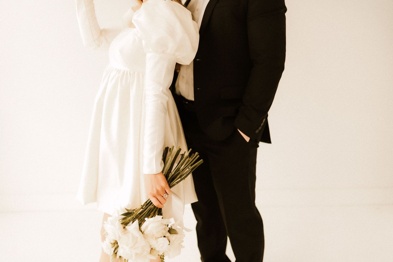 Elegant couple in black and white formal wear embracing in studio.
