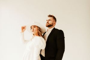 Stylish couple poses against white wall in contrasting black and white outfits.