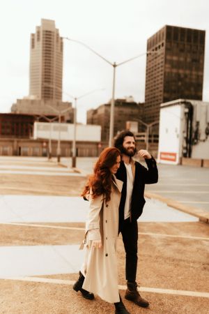 Sepia-toned cityscape photo with couple standing in an urban parking area.
