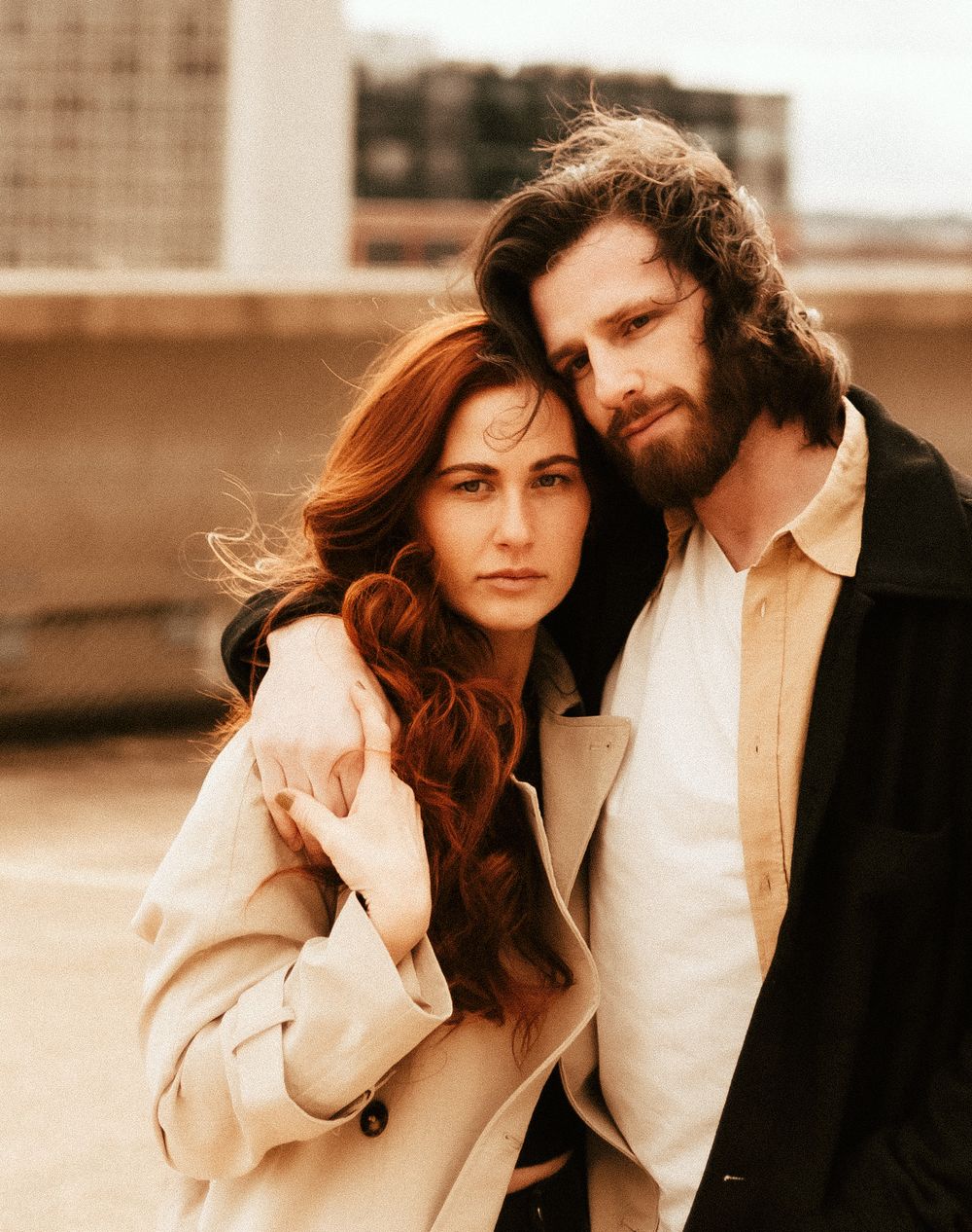 Intimate portrait of a couple in neutral tones against an urban backdrop.