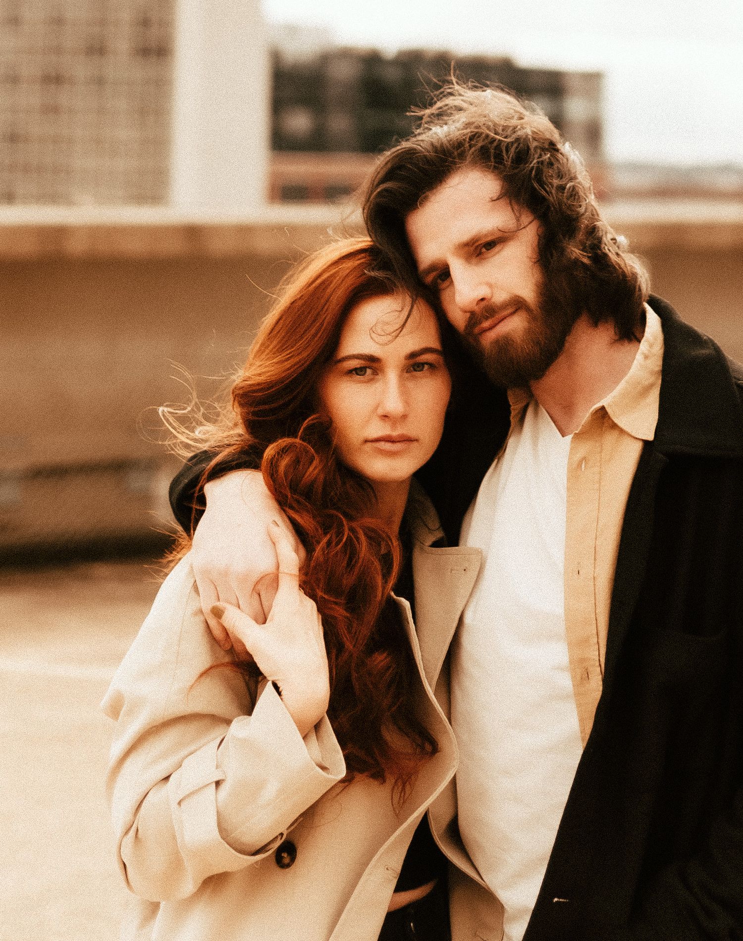 Intimate portrait of a couple in neutral tones against an urban backdrop.