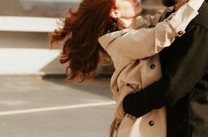 Dynamic shot of couple dancing, her beige coat flowing with the movement.
