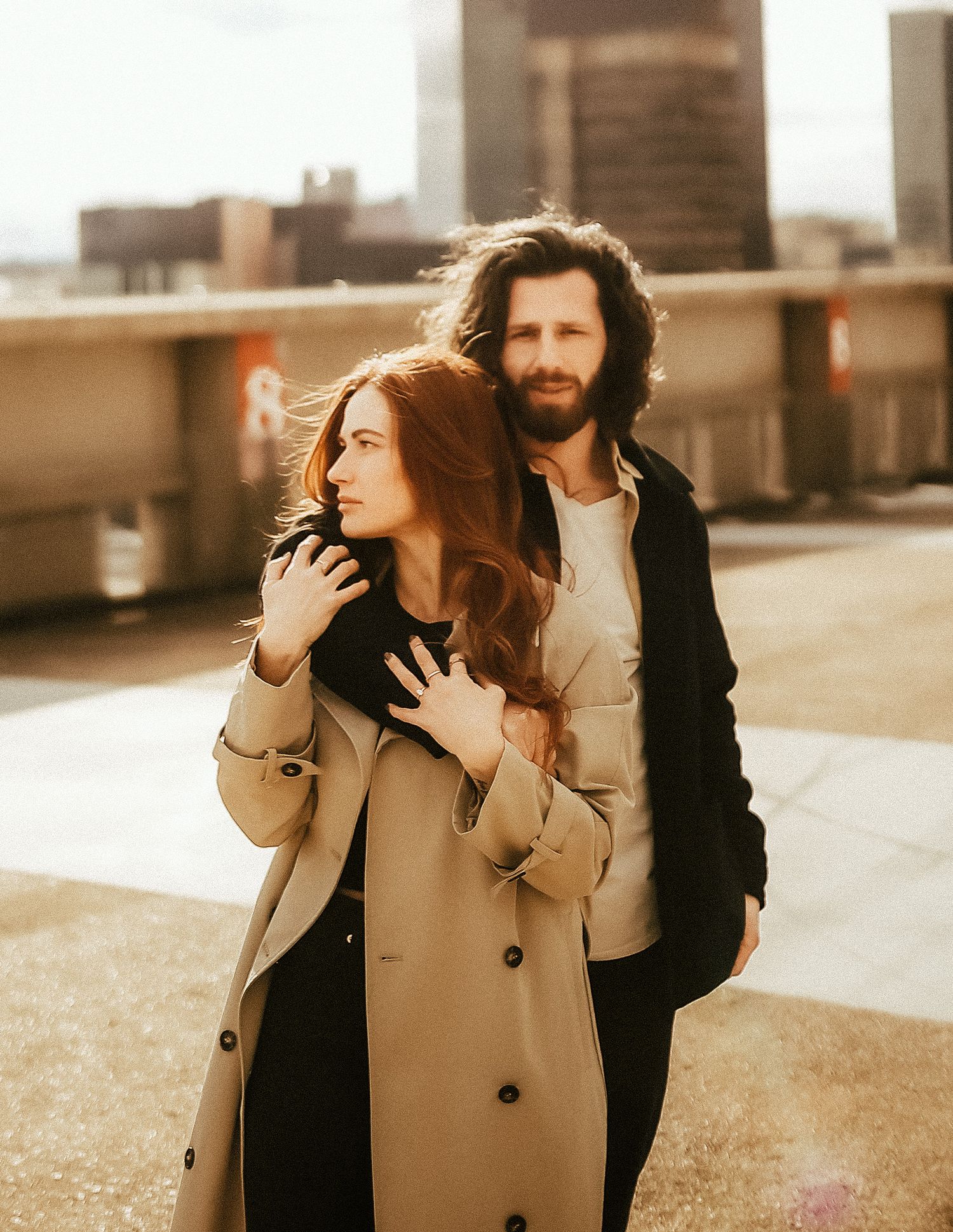 Warm-toned portrait of a couple posed against a city rooftop background.