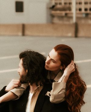 Intimate portrait of a couple with long flowing hair sharing a tender moment outdoors.