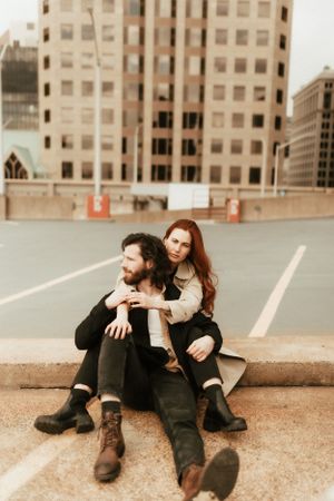 Couple sitting together on urban rooftop with modern buildings in background.