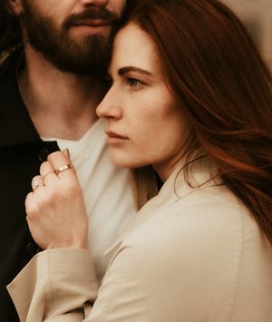 Close-up profile shot of couple in beige and black clothing against blurred background.